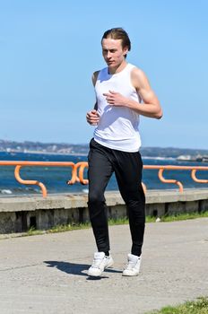 Athletic young male running on the shoreline
