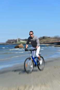Motion blur: male riding a bicycle by the sea