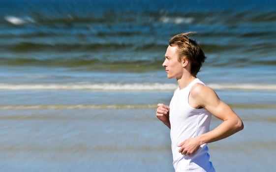 Motion blur: Athletic young male running on the beach