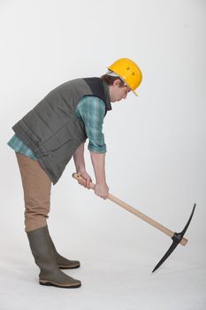 A construction worker digging with a pick axe.