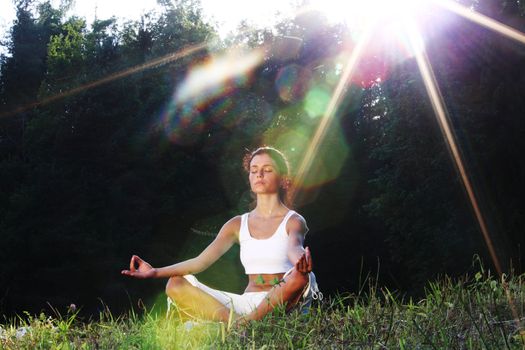 yoga woman on green grass lotus pose in sunrise light