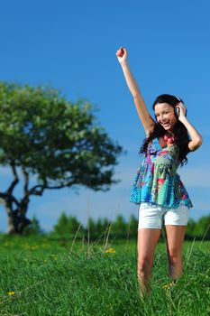 Young woman with headphones listening to music on field