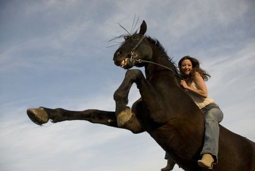 happy girl and rearing stallion in blue sky