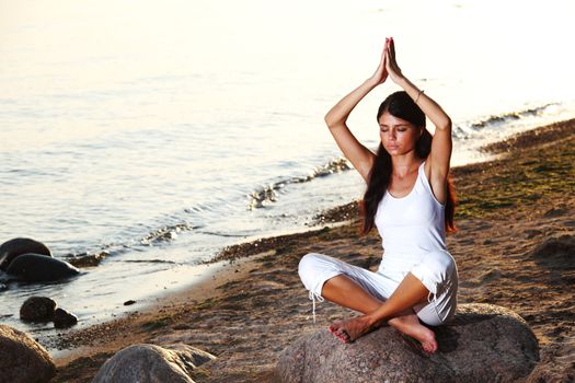 Young woman practicing yoga  near the ocean