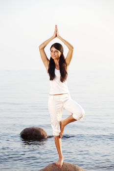 Young woman practicing yoga  near the ocean