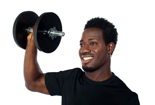 Powerful muscular young man lifting weights. Smiling and looking away