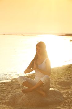 Young woman practicing yoga  near the ocean