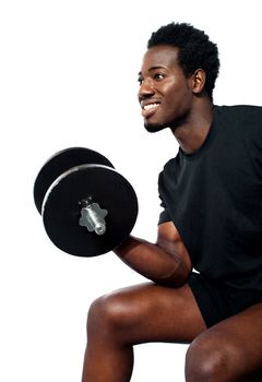 Muscular man in black sportwear with dumbbell, seated