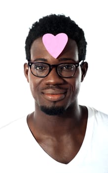 Closeup of an african man with pink paper heart on forehead isolated over white