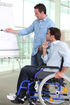 An employee pointing at a board and explaining something to a male colleague.