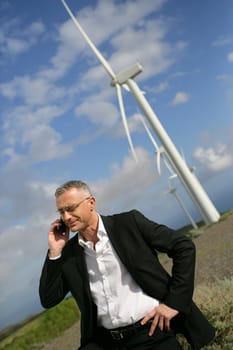 Man using his cellphone next to wind turbines
