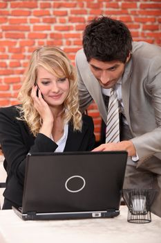 Business couple in a restaurant using a laptop and phone