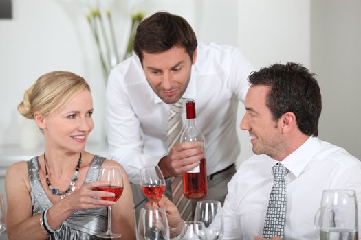 Man serving rose wine at a dinner party