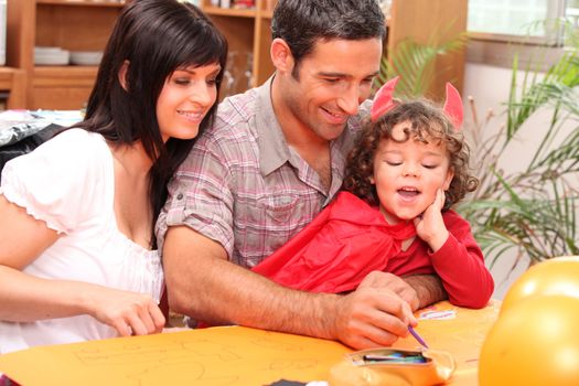 Girl dressed in a devil's costume together with her parents