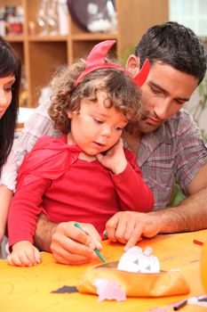 Parents helping child with Halloween decorations