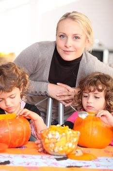 Woman helping her children carve pumpkins