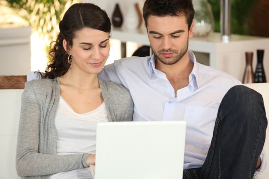 Couple using laptop in living room