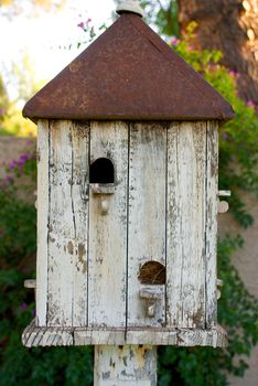 Vertical shot of an old birdhouse with a rusted metal roof