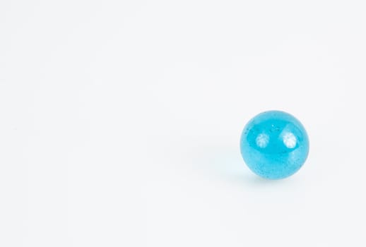 Small blue transparent glass marble on a white background