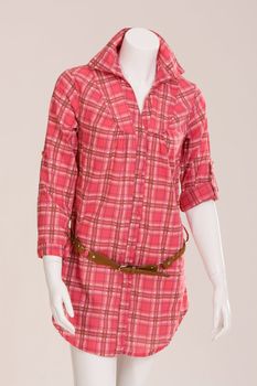Red checkered blouse with a brown belt on a mannequin