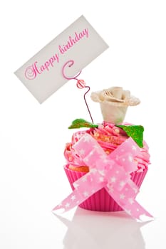 A beautiful pink happy birthday cupcake with flower and a label for your text on white background as studio shot