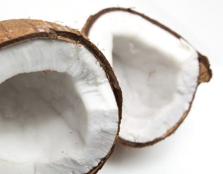 Closeup of cracked coconut on white background with light shadow. Shallow focus depth on front coconut 