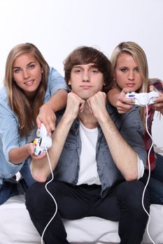 Bored teenager sat between two friends playing video games