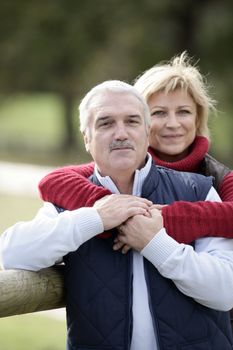 portrait of happy middle-aged couple posing in park