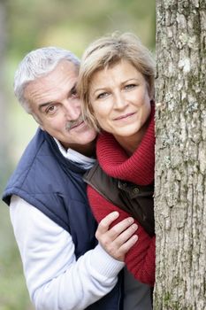 Older couple peeking around a tree