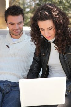 Couple using a laptop outdoors