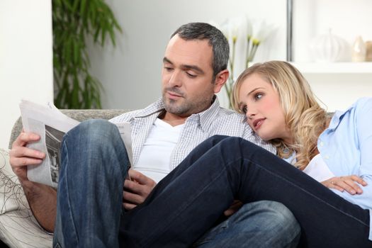 Couple on a sofa reading newspaper