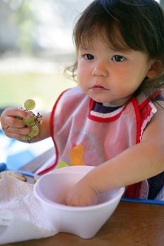 Little girl eating grapes from a bowl