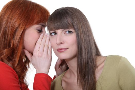 Woman whispering into her friend's ear