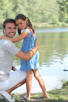 Father and daughter standing on a riverbank