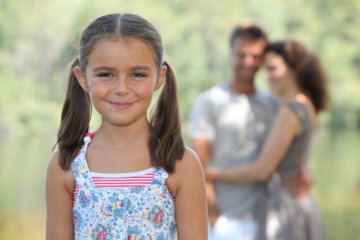 A little girl and her parents in a park.