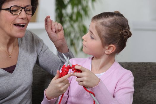 grandmother singing while her granddaughter is knitting