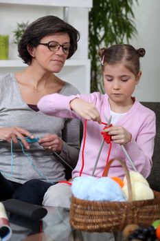 Grandmother teaching a little girl to knit