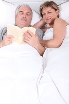 Husband reading next to his wife