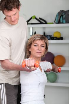Woman using dumbbells with a personal trainer