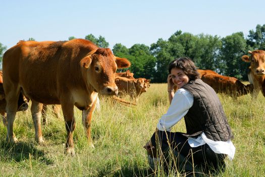 Farmer kneeling by cows in field