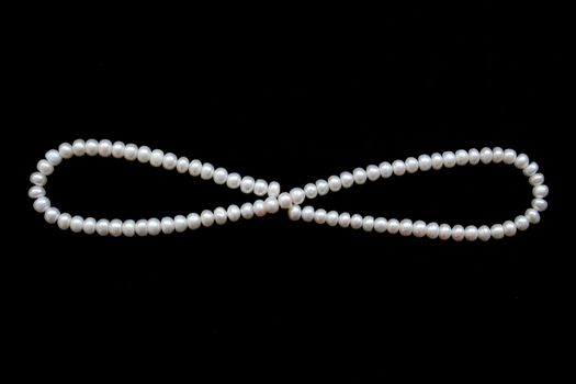 White pearls on the black silk as background 
