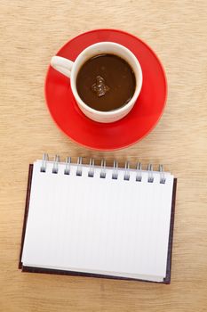 red cup of hot coffee and book on wood background