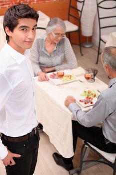 an old couple eating at restaurant and a young waiter