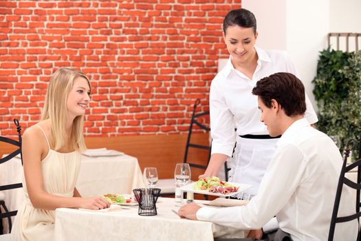 Waitress serving a young couple in a restaurant