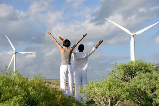 Couple doing yoga by wind farm