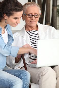 Young woman helping an elderly lady navigate the internet