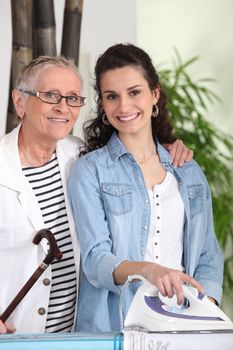 Young woman ironing for an elderly lady