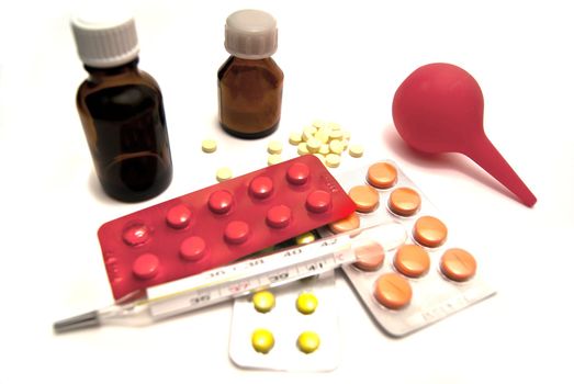 Pills, enema and thermometer close-up on white background