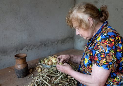 The old woman cuts an onions at itself in the house