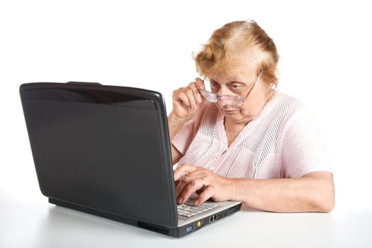The old woman in glasses looks at the screen notebook on a white background